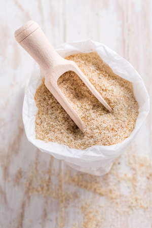 Heap of psyllium husk in small bag on wooden table table. Psyllium husk also called isabgol is fiber derived from the seeds of Plantago ovata plant found in India.の写真素材