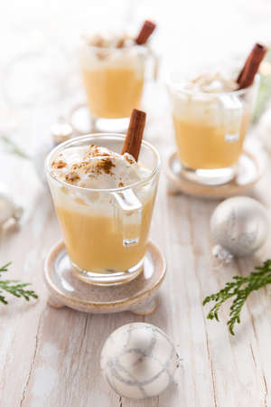 Eggnog with cinnamon and nutmeg for Christmas and winter holidays. With Xmas decorations on wooden background.の写真素材