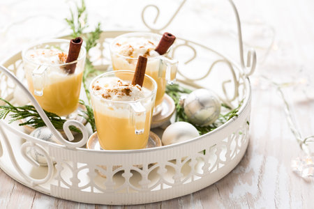 Eggnog with cinnamon and nutmeg for Christmas and winter holidays. With Xmas decorations on wooden background.の写真素材