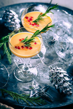 Traditional egg liqueur or eggnog with cinnamon, pomegranate and rosemary  with Christmas decorationの写真素材