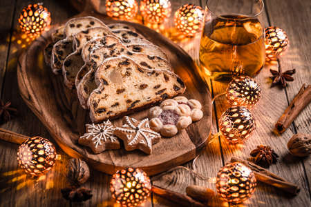 Christmas Stollen and cookies with apple mulled wine and Christmas lights. Traditional Sweet Fruit Loaf with icing sugar.の写真素材