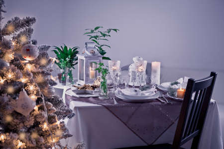 Table setting for celebration Christmas and New Year Holidays. Festive table at home with Christmas tree in violet tone.の写真素材