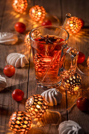 Spicy winter tea or punch with anise and meringue pastry with Christmas lightsの写真素材