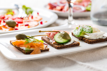 Variation of healthy open sandwiches on Pumpernickel bread with vegetables, salmon, ham and...