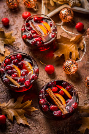 Mulled wine with orange, cranberries,  cinnamon, anise with autumn leaves and Christmas lightsの写真素材