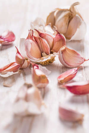 Garlic bulb and garlic cloves on white wooden backgroundの写真素材