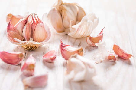 Garlic bulb and garlic cloves on white wooden backgroundの写真素材