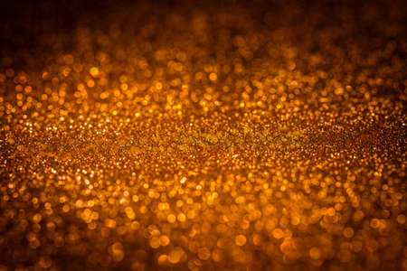 Blurry and abstract Christmas glitter background in golden tone. Out of focus.の写真素材