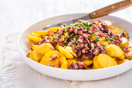 German fries - fried potatoes with bacon and onion topping on plateの写真素材