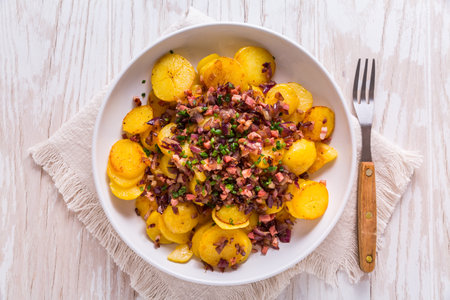 German fries - fried potatoes with bacon and onion topping on plateの写真素材