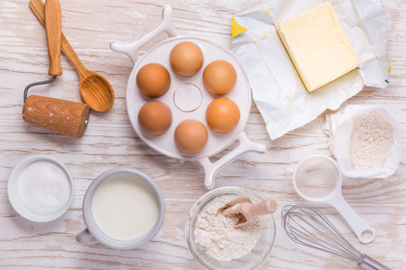 Assorted baking ingredients and kitchen utensils for cooking and baking on wooden background