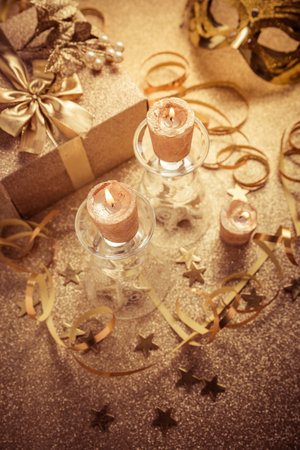 Home decoration with candles and gift box in golden tone on golden background.  New Year, holiday or birthday partyの写真素材