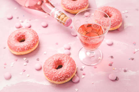 Rose wine or cocktail with pink donuts and pink chocolate beans on pink backgroundの写真素材