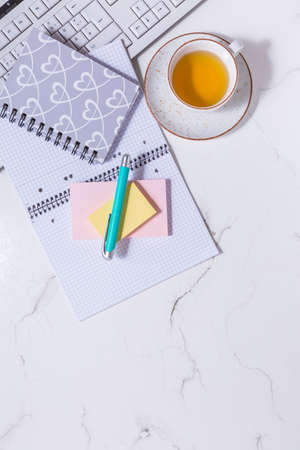Flat lay home business desk -  cup of tea, with communication device with and writing tools. Feminine business mockup, copyspace, white background.の写真素材
