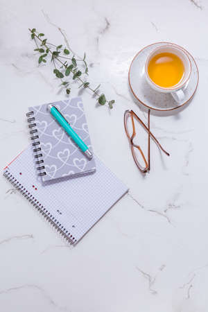 Flat lay home business desk -  cup of tea, with communication device with and writing tools. Feminine business mockup, copyspace, white background.の写真素材