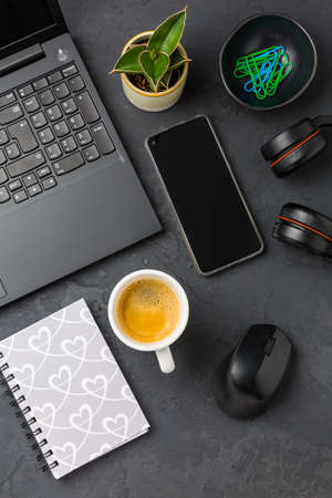 Working place and office desk with coffee, laptop, headset and smarthpone. Flatlay in black tone.の写真素材