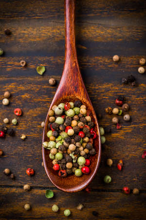 Colorful pepper corns in wooden spoon on wooden backgroundの写真素材