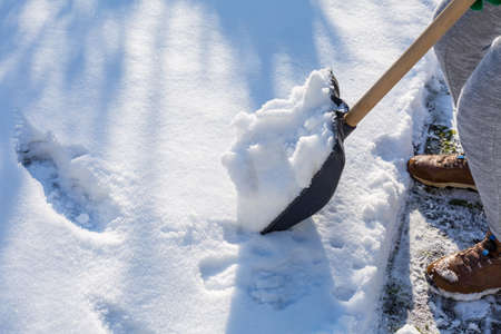 Child shoveling and removing snow in front of his house in the suburbの写真素材