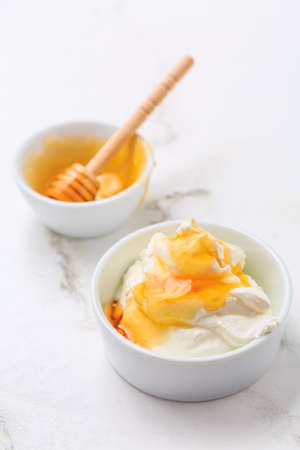 Greek yoghurt with honey on marble table. Healthy eating concept.の写真素材