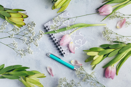 Workspace with diary, notebook, pen, flowers on light blue background. Home office desk. Top view feminine background. Flat lay, top view.の写真素材