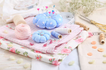 Sewing tools and supplies  - handmade pincushion, scissors, bobbins with thread, needles and fabric. Hobby, crafting, creativity, free time at home concept.の写真素材