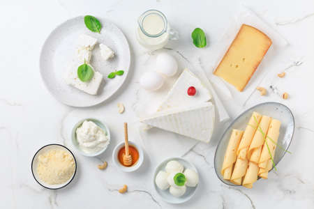 Fresh dairy products on white marble background. Assortment of cheese, honey, milk, yogurt. Top view.の写真素材