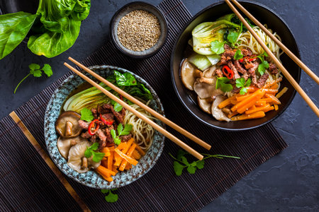 Asia style ramen soup with udon noodle, beef, shiitake, pak choi cabbage and carrots on black...