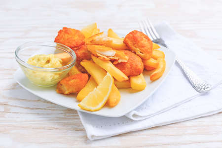 Fish and chips with dip and lemon on white plateの写真素材