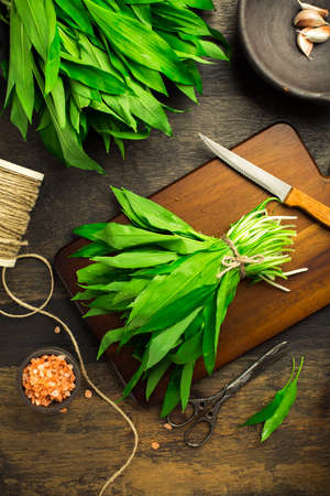 Bunch of Ramson or bear leek (Allium ursinum) with pink Himalayan salt on cutting board.の写真素材