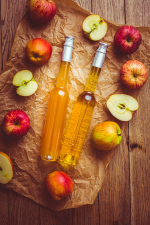 Apple juice with apple vinegar in bottles and fresh apples on wooden backgroundの写真素材