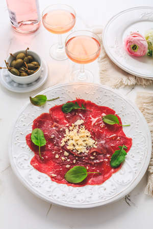 Beef carpaccio with capers and parmesan cheese as appetizer with rose wineの写真素材