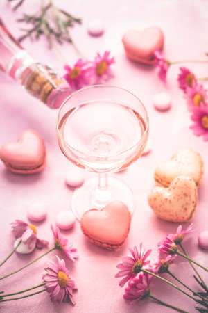 Happy Mothers Day - sweet macarons in heart shape and glass of rose sparkling wine with flowers in pink toneの写真素材