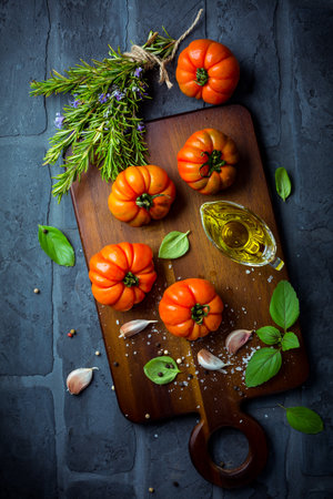 Italian cuisine - Olive oil, tomato and herbs on rustic cutting boardの写真素材