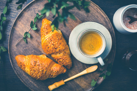 Breakfast - Croissants with nuts and cup of coffee on morning tableの写真素材