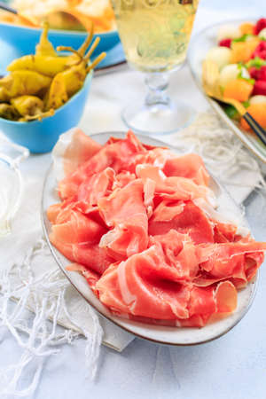 Prosciutto with grilled peppers -  Italian dry ham with grilled green peppers on wooden tableの写真素材