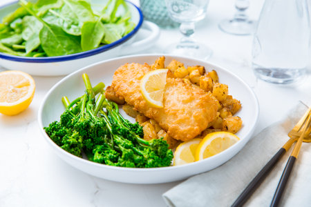 Breaded fisch fillet with spicy baked potatoes and broccoli (bimi) salad with lemon