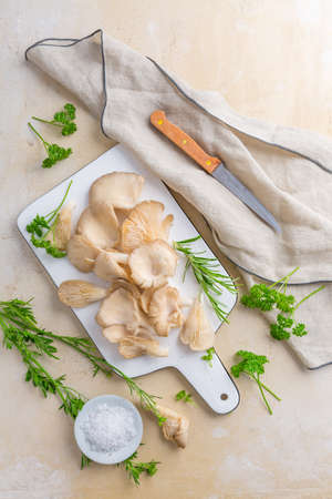 Organic oyster mushrooms with herbs and salt on cutting boardの写真素材