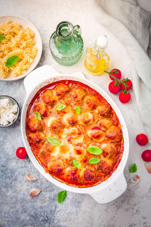 Homemade meatballs in tomato mozzarella sauce with basil and pasta in casseroleの写真素材