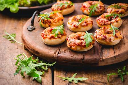 Small pizza in donut shape with rocket (arugula) and fresh salad on wooden backgroundの写真素材
