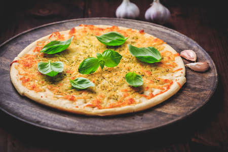 Pizza bread with garlic, cheese and basil on wooden backgroundの写真素材