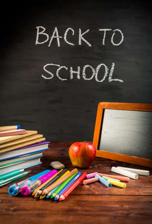 Pile of book and exercise books with shool applies and apple snack with chalkboard.  Back to school concept.の写真素材