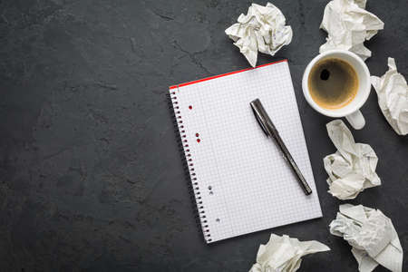 Office workplace - cup of coffee with empty notebook and pen on black backgroundの写真素材