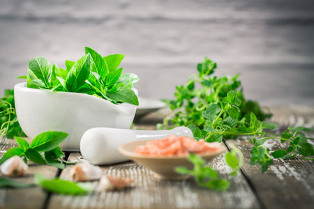 Thai basil, parsley, thyme and other herbs with Himalaya and mortar on wooden kitchen tableの写真素材