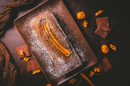Homemade vegan banana bread or cake with nuts, chocolate and cinnamon on brown backgroundの写真素材