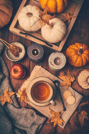 Hot tea with cookies, apple and fall foliage and pumpkins on wooden backgroundの写真素材