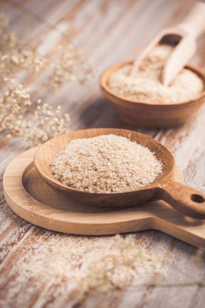 Heap of psyllium husk in wooden bowl on wooden table table. Psyllium husk also called isabgol is fiber derived from the seeds of Plantago ovata plant found in India.の写真素材