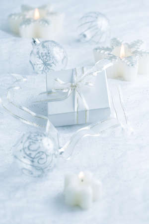 Arrangement of Christmas ornaments, candles and smal present in snowy whiteの写真素材