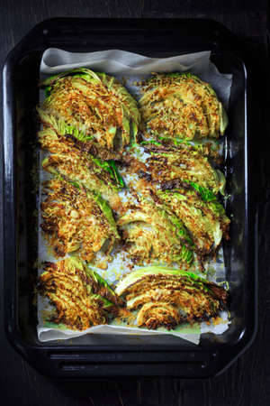 Baked savoy cabbage with parmesan cheese, honey and spices on baking sheetの写真素材