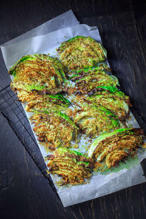 Baked savoy cabbage with parmesan cheese, honey and spices on baking sheetの写真素材