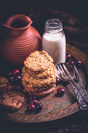Homemade oatmeal cookies, cranberry cookies and bottle of milk on wooden tableの写真素材